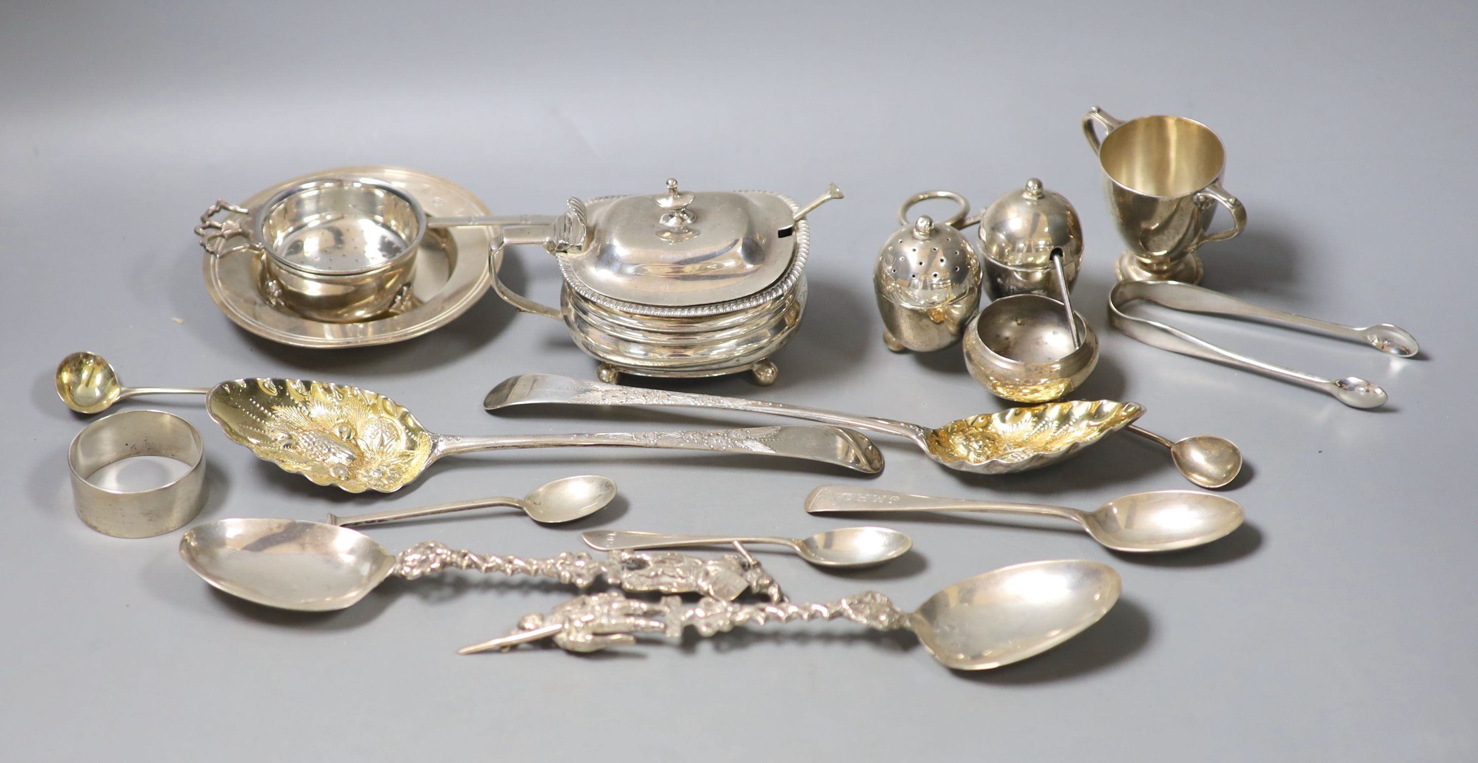 A group of small silver including a Georgian silver mustard, marks rubbed, a pair of Georgian silver berry spoons, two continental spoons, a small Victorian silver cruet stand, a tea strainer on stand, napkin ring, small